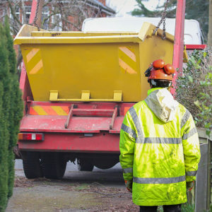 Skip being transported to a driveway to promote Greenfield Risk Solutions Insurance Brokers -Motor Fleet - Skip hire, waste and recycling insurance