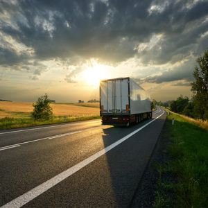 Lorry driving down road in sunset to promote Greenfield Risk Solutions Insurance Brokers - Wholesale and Distribution Insurance