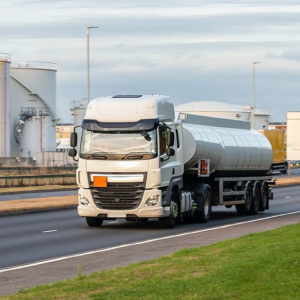 Specialist HGV driving on a road by factories to promote Greenfield Risk Solutions Insurance Brokers - Motor Fleet Insurance - Hazardous Goods Fleet