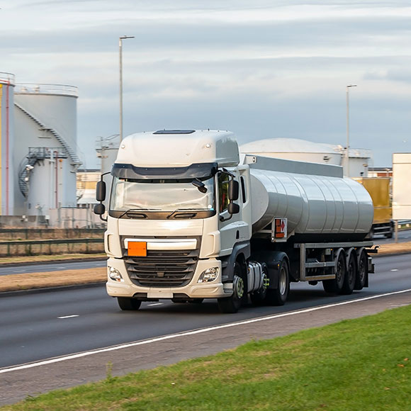 Specialist HGV driving on a road by factories to promote Greenfield Risk Solutions Insurance Brokers - Motor Fleet Insurance - Hazardous Goods Fleet