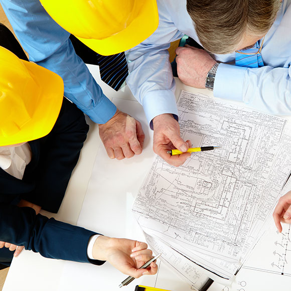 Construction workers leaning over site details to promote Greenfield Risk Solutions Insurance Brokers - Financial Lines - Professional Indemnity Insurance
