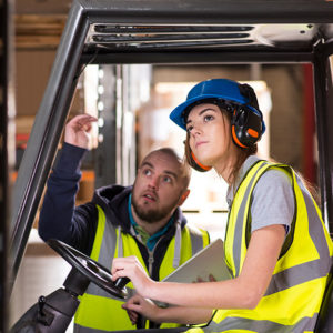 A female learner getting direction before operating a forklift truck to promote Greenfield Risk Solutions Insurance Brokers- Driver Training Insurance
